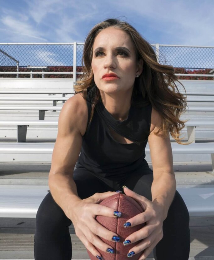 A woman holding a football in the stadium bleachers